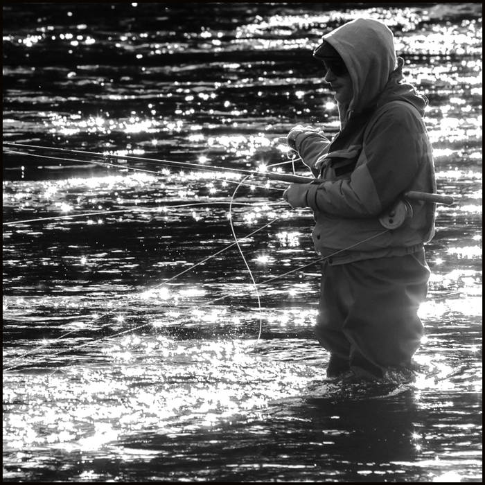 A fisherman stands expectantly in the river in the middle of the city centre © John MacPherson